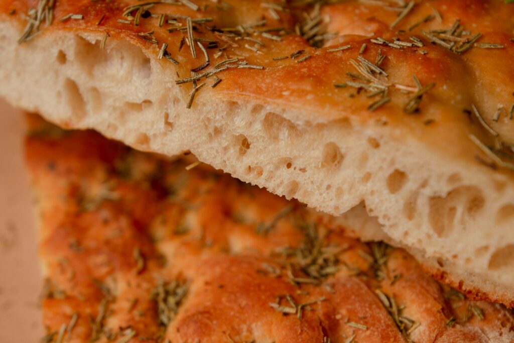 Fresh, golden focaccia bread topped with herbs, perfect for culinary projects.